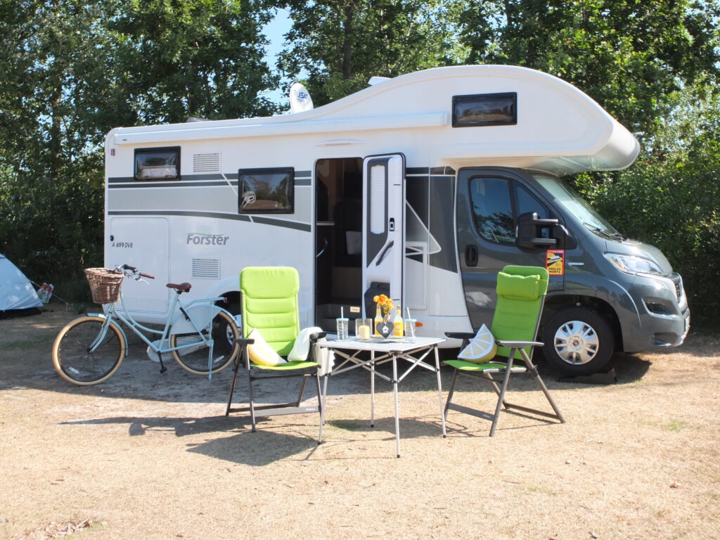 Camper mit Campingtisch und zwei Stühlen und schöner Deko auf dem Tisch